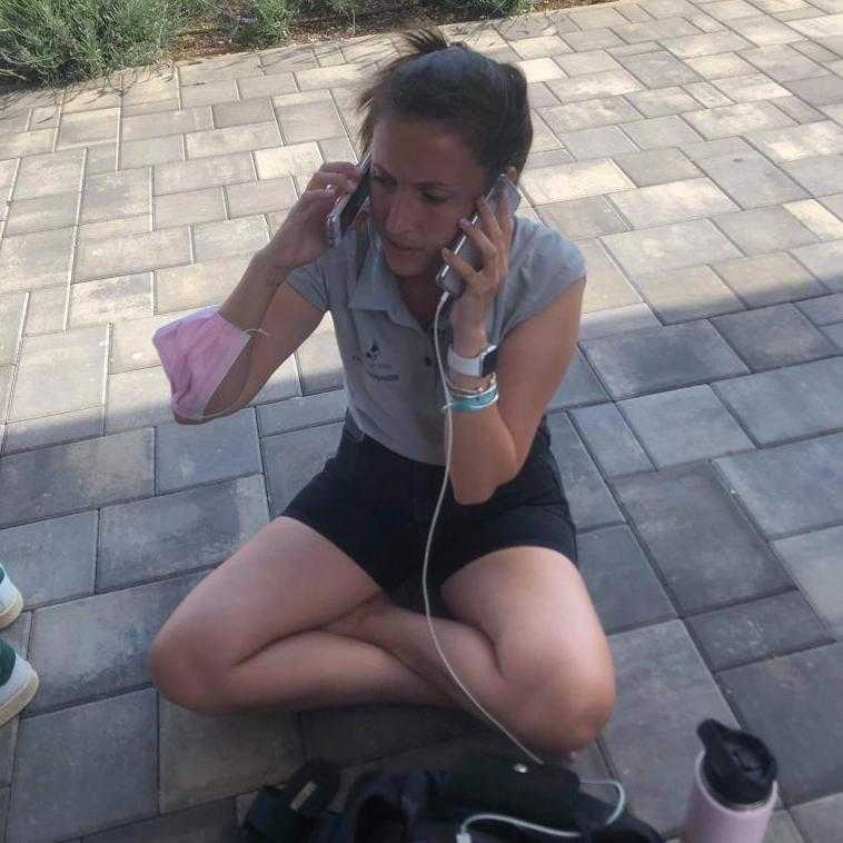Rebecca sitting on the floor with two phones in her hand